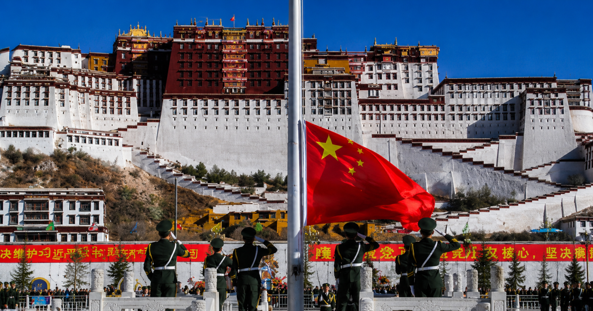 legge unità etnica Cina, bandiera cinese davanti a un monastero tibetano, simbolo del controllo di Pechino sulle minoranze